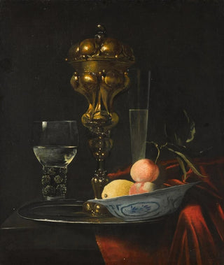 Christiaen Striep - Still life with a gilt cup on a silver plate a porcelain bowl with fruit a roemer and a wine glass all on a wooden table draped in red fabric.webp