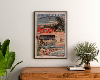 Manifesto Bretagna vintage – Spiagge della Bretagna, ferrovie, incorniciato sopra una cassettiera in legno, tra piante.
