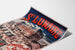 Manifesto vintage Bretagna – Saint-Lunaire, bagni di mare, presentato su una pagina piegata, visto in prospettiva.