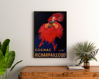 Manifesto pubblicitario vintage Cognac Richarpailloud, incorniciato sopra una cassettiera in legno, tra delle piante.