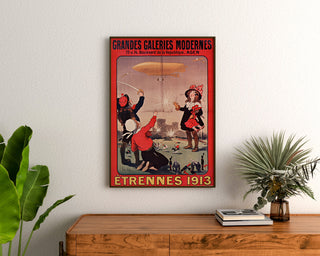 Manifesto pubblicitario vintage Grandes Galeries modernes, Agen, incorniciato sopra un comò in legno, tra piante.