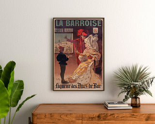 Manifesto pubblicitario vintage La Barroise, incorniciato sopra una credenza in legno, tra delle piante.