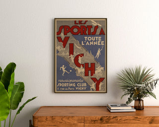 Manifesto turistico vintage – Vichy, gli sport tutto l’anno, incorniciato sopra una cassettiera in legno, tra piante.