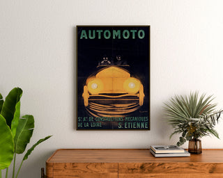 Manifesto vintage Automoto, Saint-Étienne, incorniciato sopra una cassettiera in legno, tra piante.