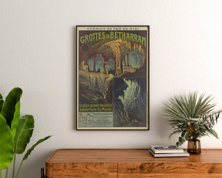 Manifesto vintage Grotte di Bétharram, incorniciato sopra una cassettiera in legno, tra piante.