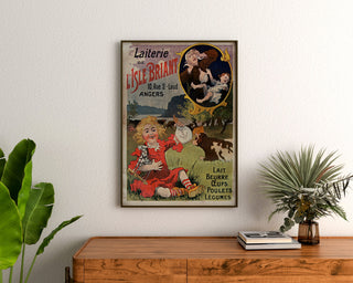 Manifesto vintage Laiterie de l’Isle Briant, Angers, incorniciato sopra un comò in legno, tra piante.