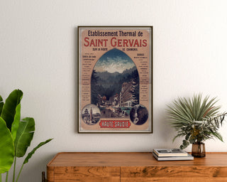 Manifesto vintage Saint-Gervais, stabilimento termale, incorniciato sopra una cassettiera in legno, tra piante.