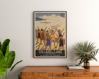 Manifesto vintage Villard-de-Lans, SNCF, incorniciato sopra una cassettiera in legno, tra piante.