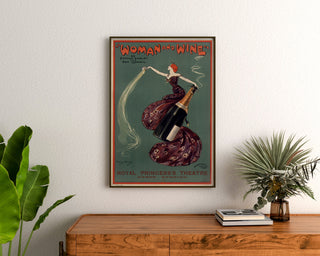 Manifesto vintage Woman and Wine, Princess’s Theatre, incorniciato sopra una cassettiera in legno, tra piante.